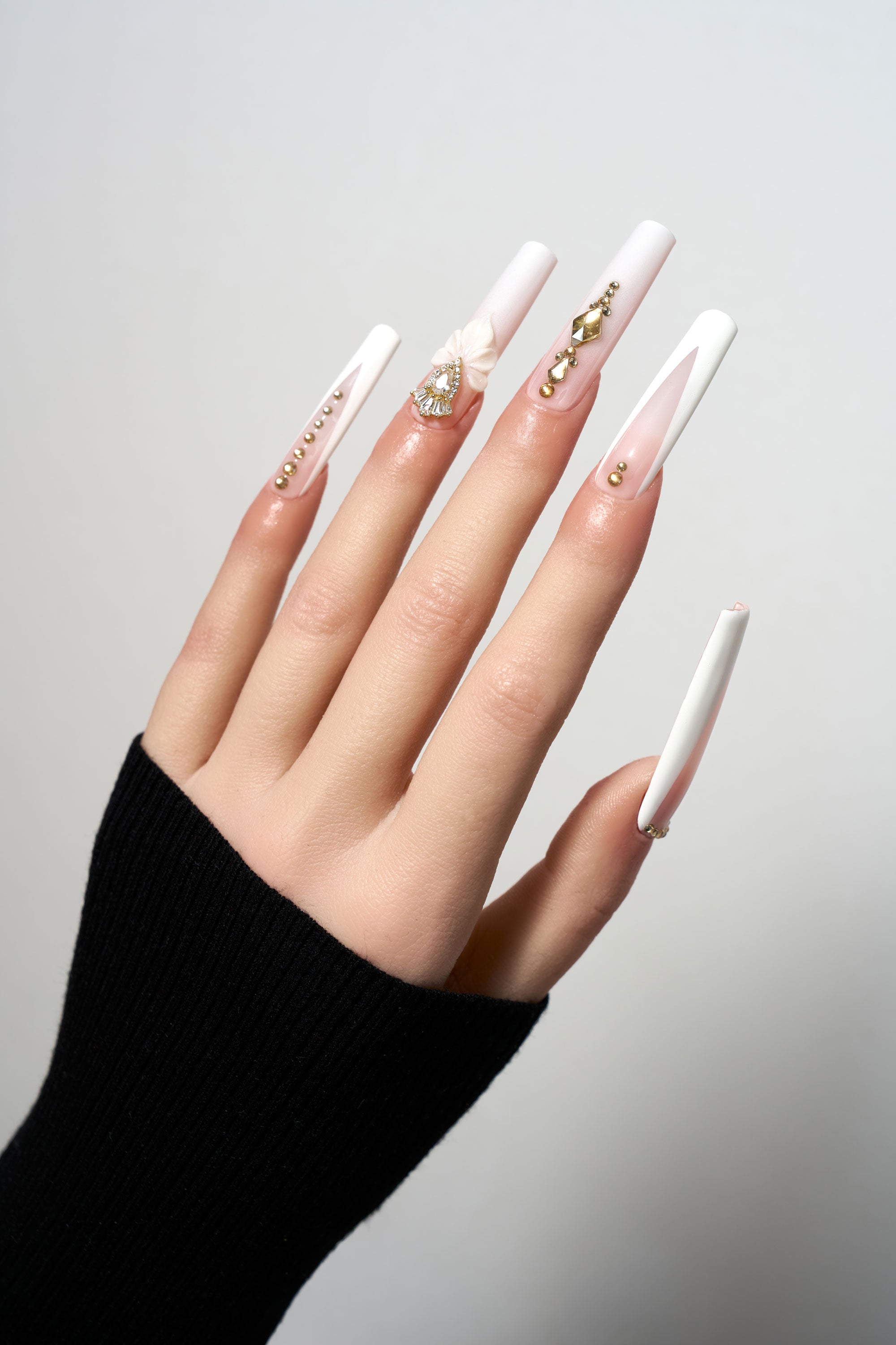 Blush Lotus reusable extra-long coffin press-on nails in matte white, featuring elegant gold stud trails, 3D sculpted lotus flower accents, and focal teardrop gemstones.