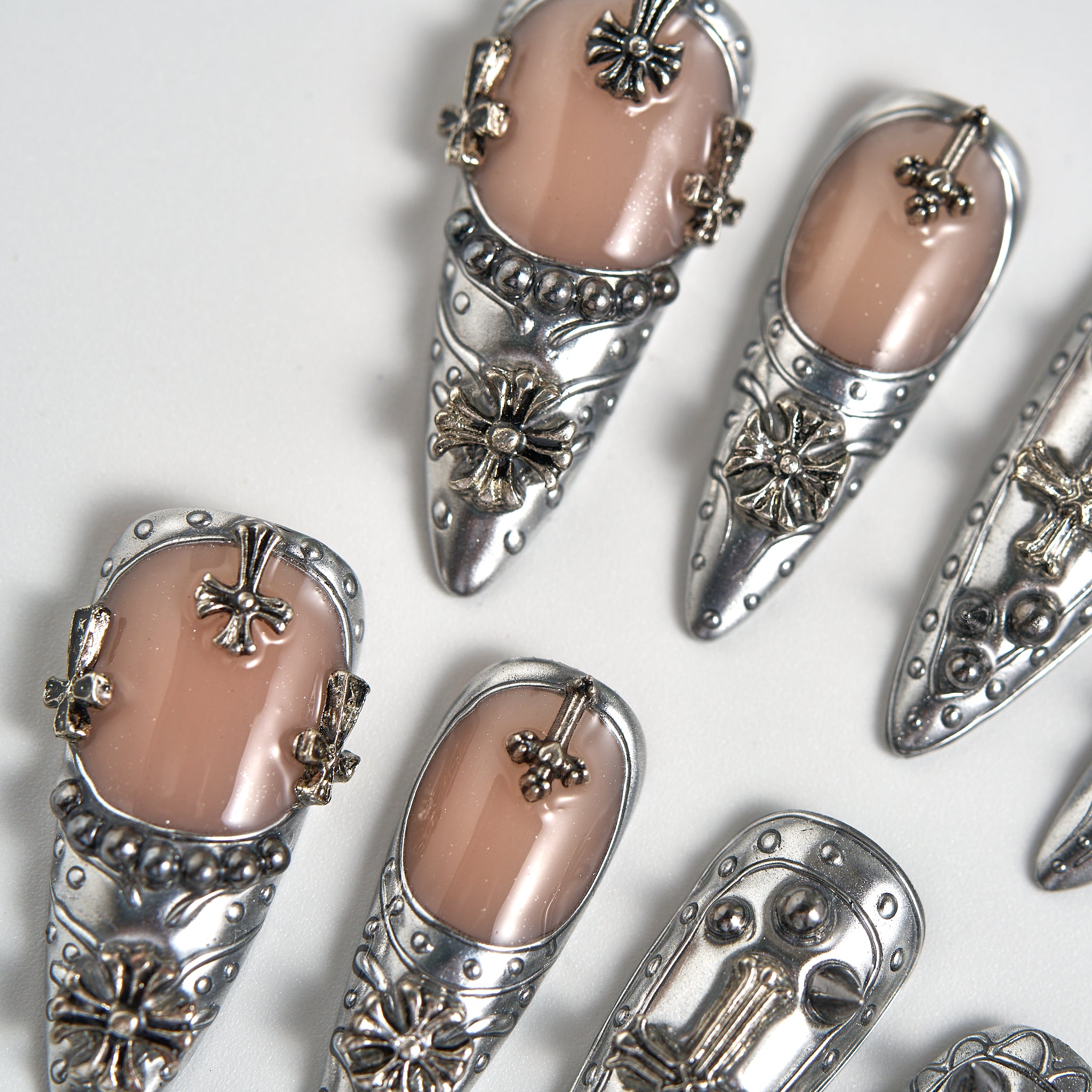 Chrome Reign stiletto press-on nails in metallic chrome silver, close-up of salon-quality reusable nails with 3D cross and floral details on a white background