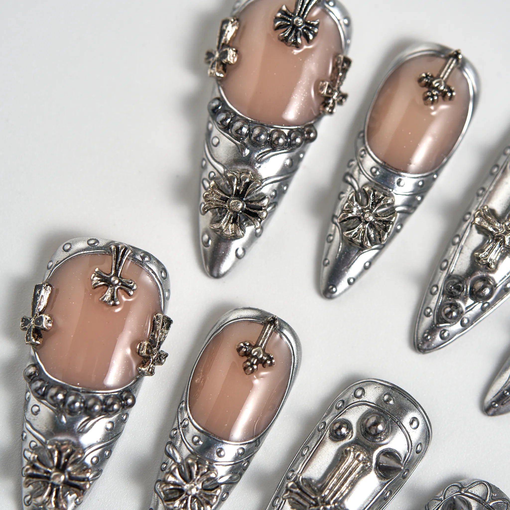 Decorative nail art with silver and gold accents on a white background