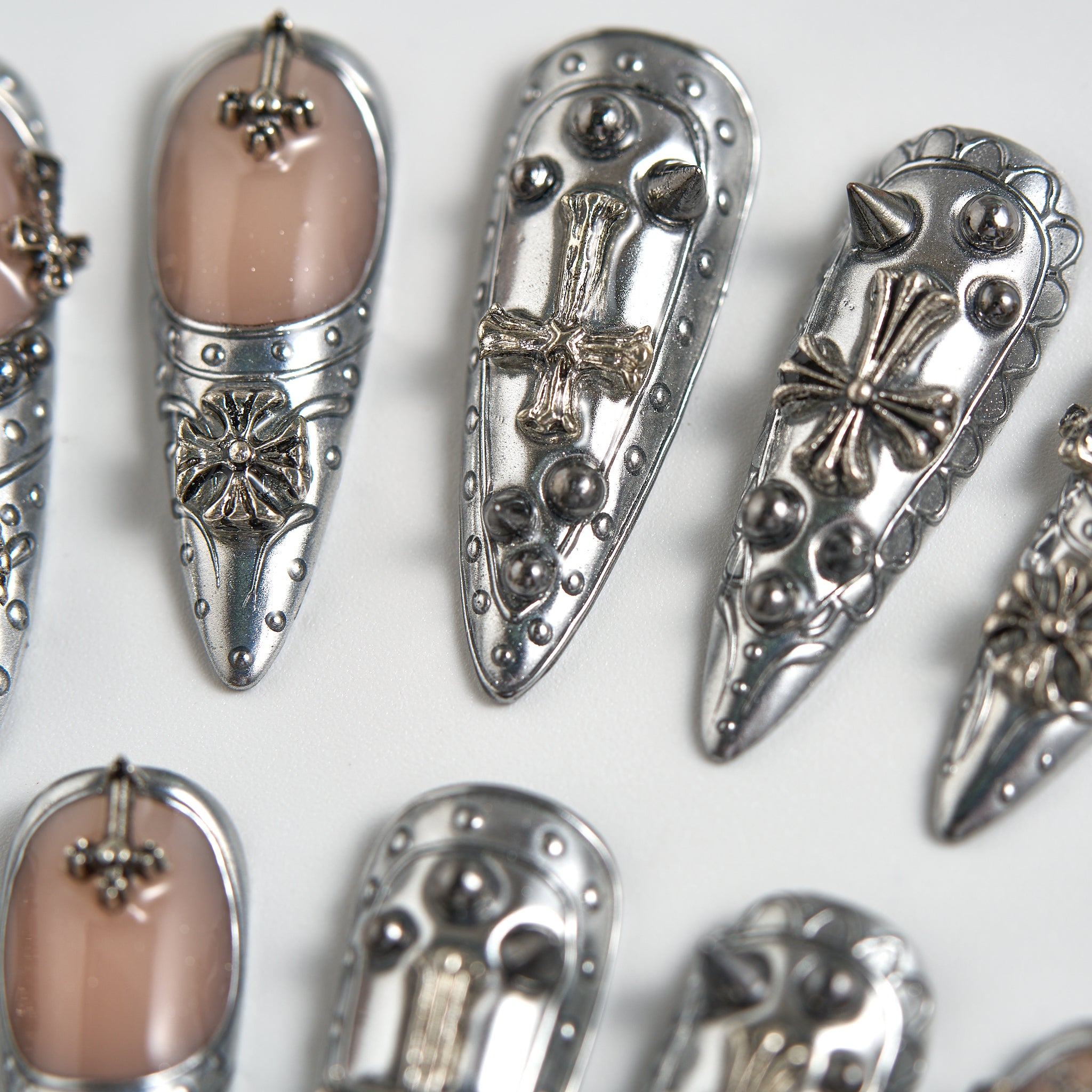 Chrome Reign stiletto press-on nails in metallic chrome silver, close-up detail with cross and 3D embellishments, salon-quality reusable nails on white background