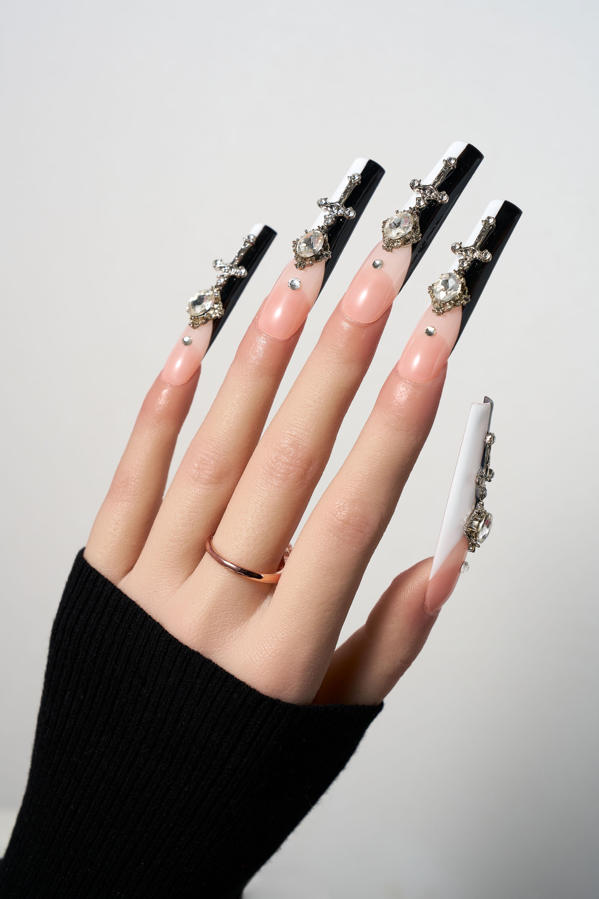 Divine Plea reusable extra-long coffin press-on nails featuring a striking black and white split design, adorned with 3D silver sword charms and focal clear gemstones for a dramatic gothic look.