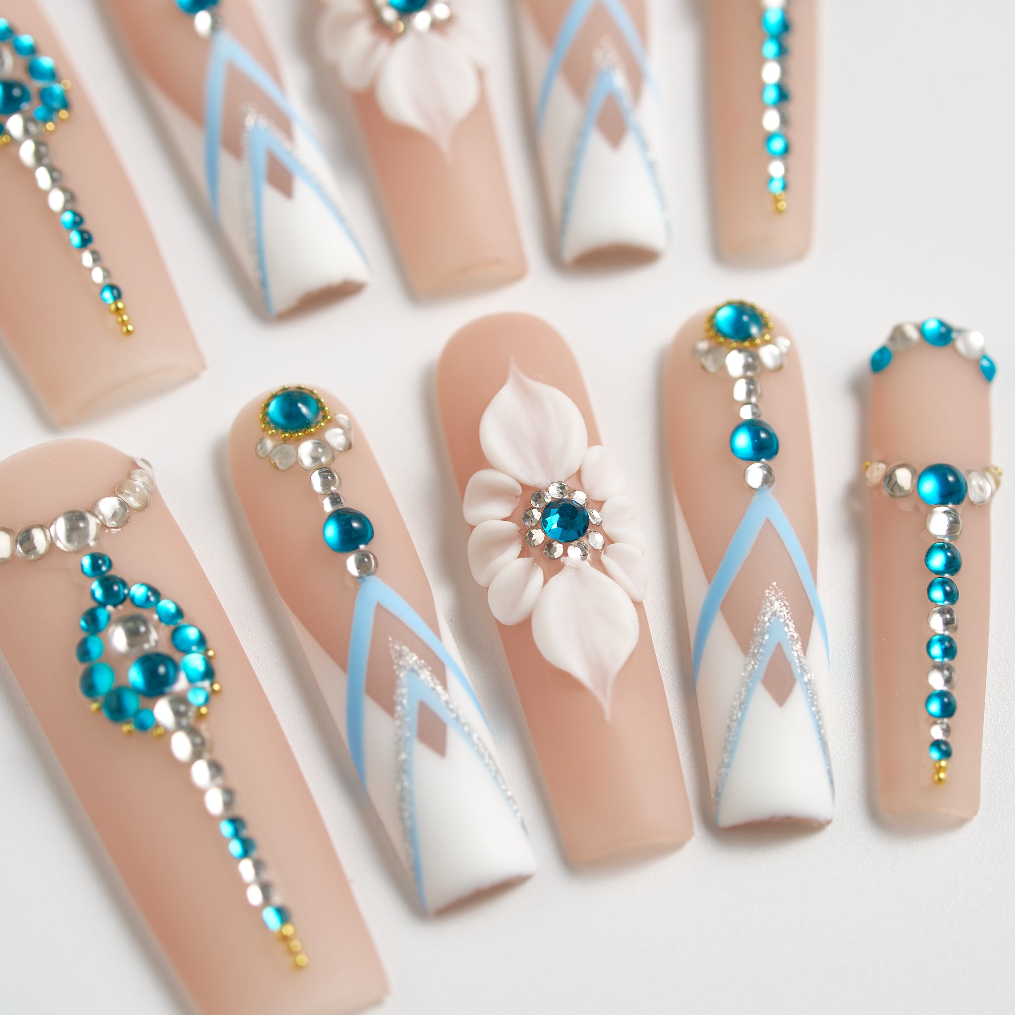 Centered view of ‘Frost Waltz’ long square press-on nails featuring 3D white floral design, blue rhinestones, silver beads, and geometric white-blue detailing.