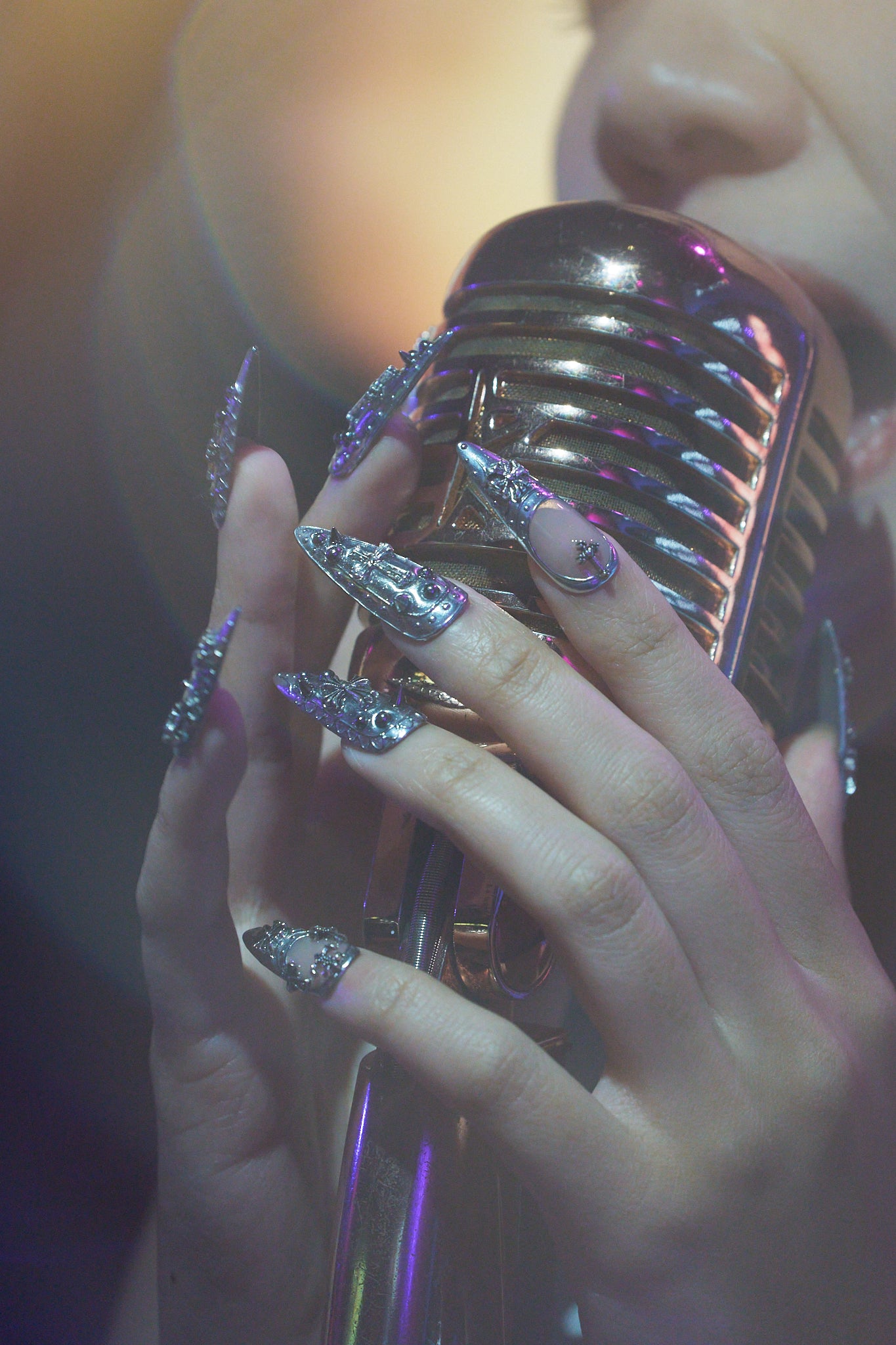 MiuNail Chrome Reign metallic nail extensions, dramatic silver gothic nail art, holding a vintage microphone, live performance aesthetic.