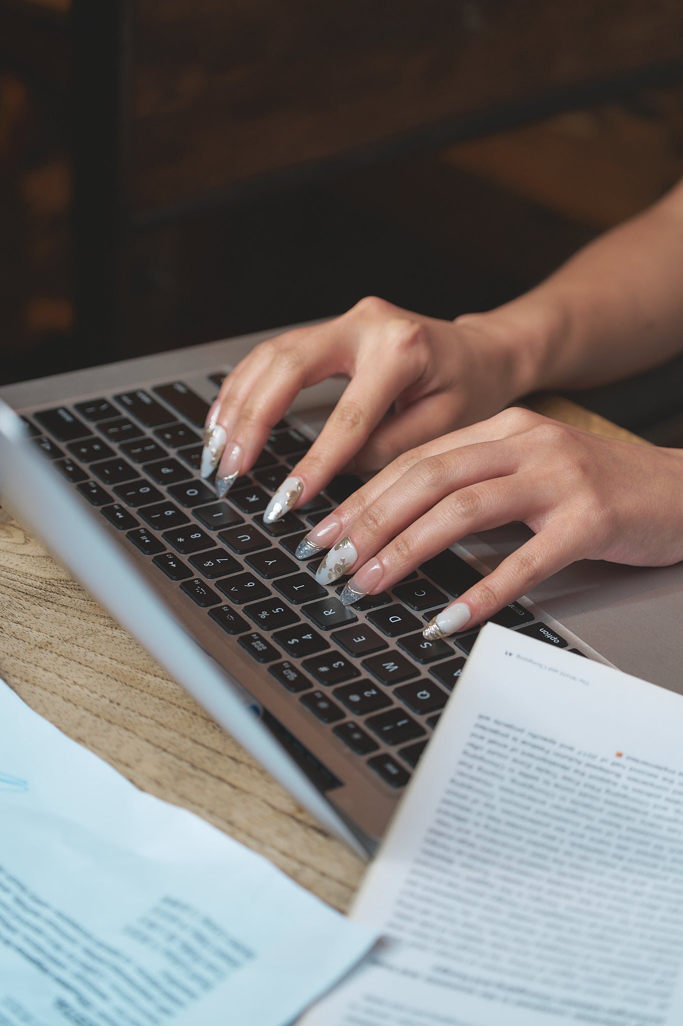 Petal Bloom long almond press-on nails in marble white and gold, hands typing on a laptop with documents on desk