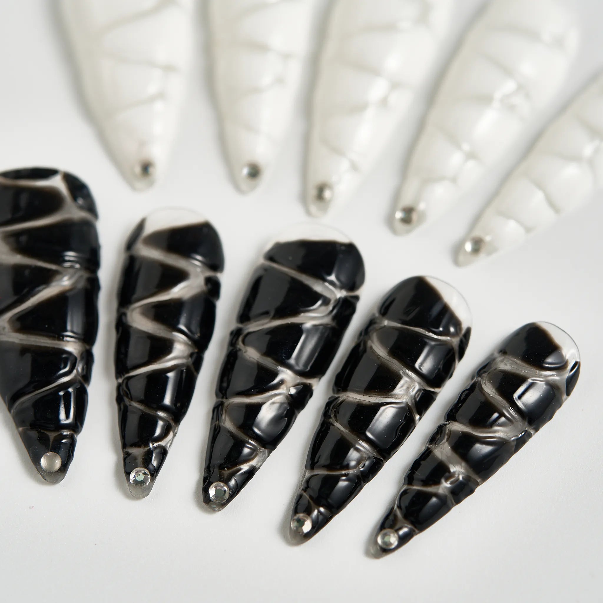 Black nail art designs with silver accents on a white background