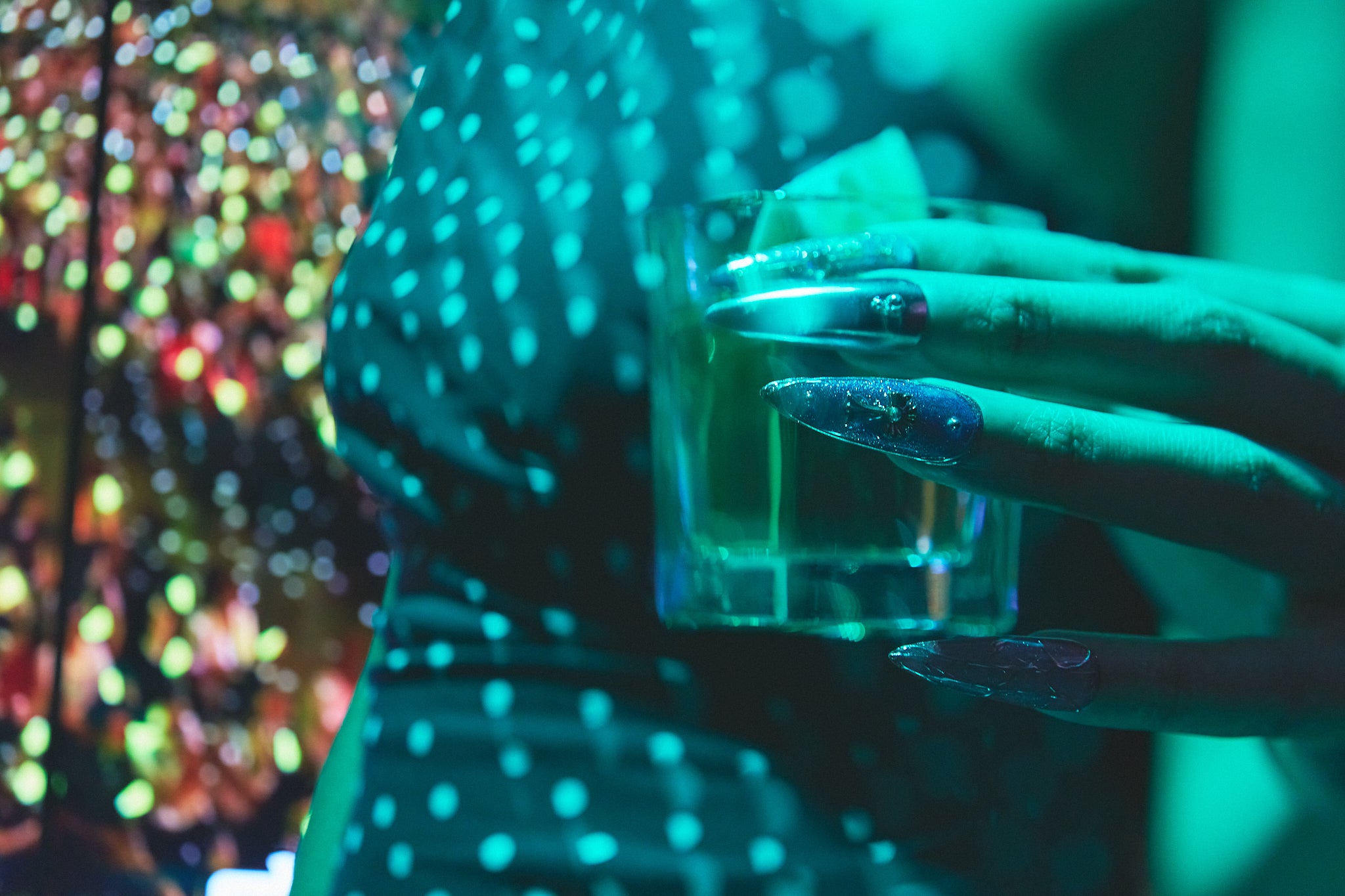 Violet Eclipse stiletto press-on nails in metallic purple and gold, hand holding a glass at a party, instant manicure style