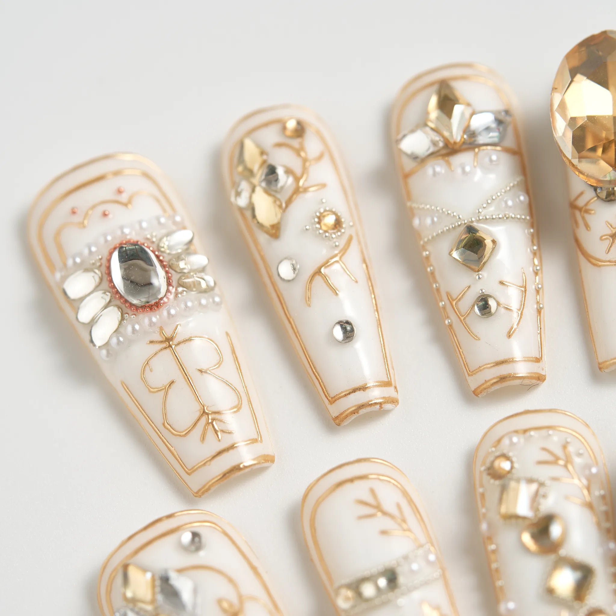 Decorative nail art with gold and silver accents on a white background