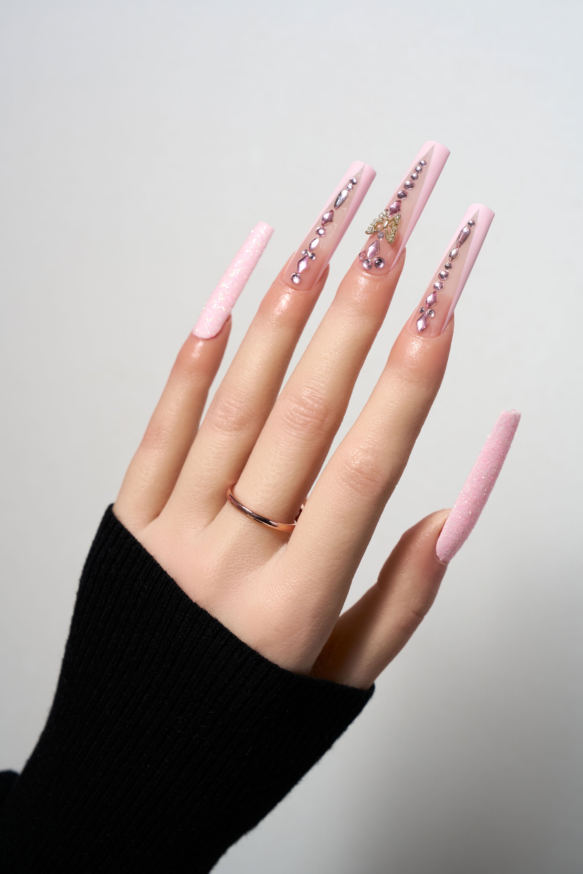 Sugar Flutter reusable extra-long coffin press-on nails featuring a matte baby pink base with vertical rhinestone trails, shimmering glitter accents, and a 3D gold butterfly charm.