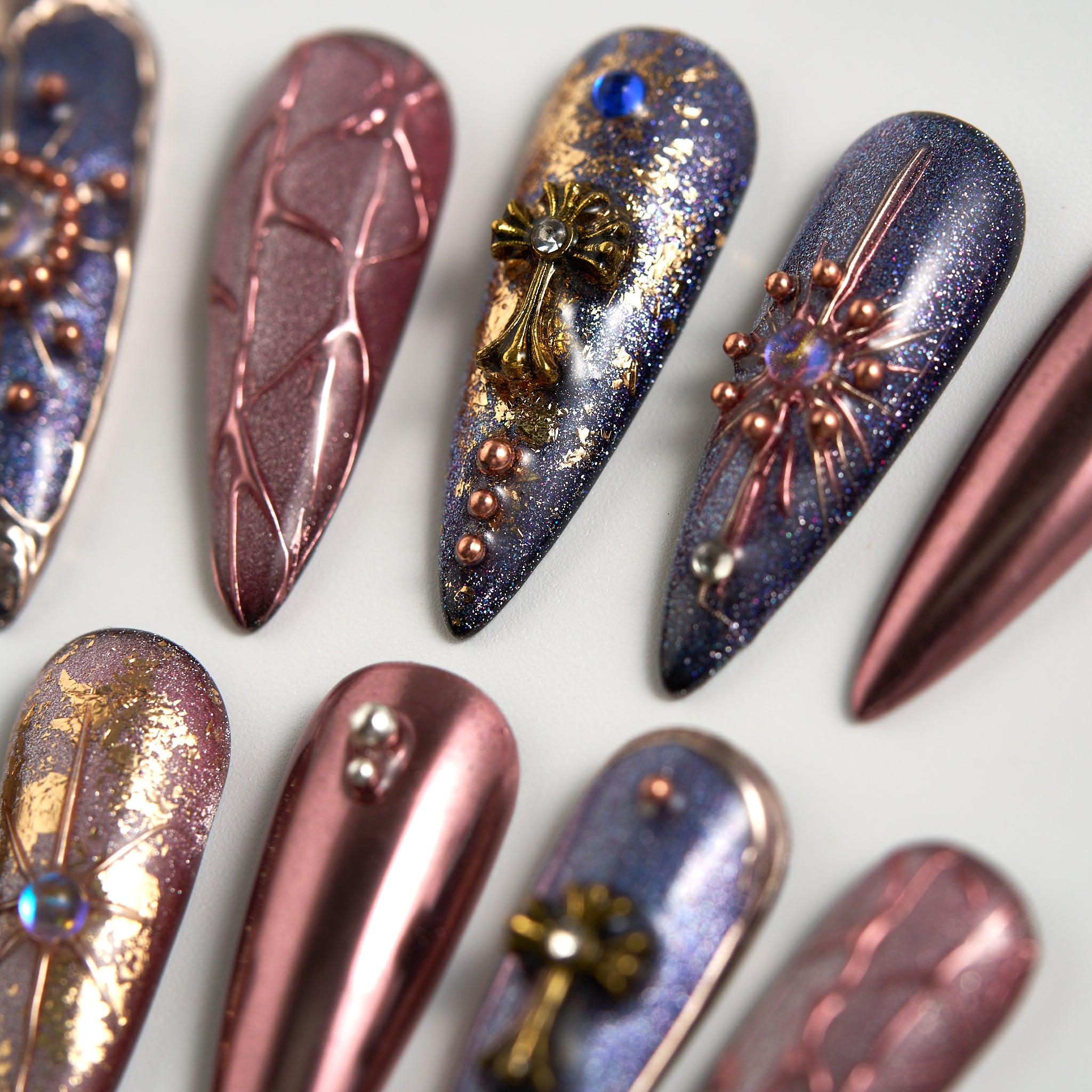 Violet Eclipse reusable press-on nails, long stiletto shape in metallic purple and gold, close-up with decorative elements