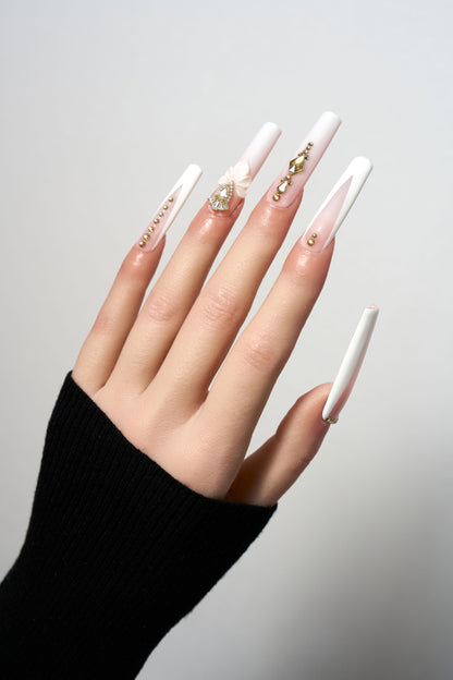 Blush Lotus reusable extra-long coffin press-on nails in matte white, featuring elegant gold stud trails, 3D sculpted lotus flower accents, and focal teardrop gemstones.