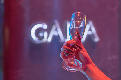 Hand with long stiletto ‘Desert Halo’ press-on nails holding a champagne glass at a GALA event.