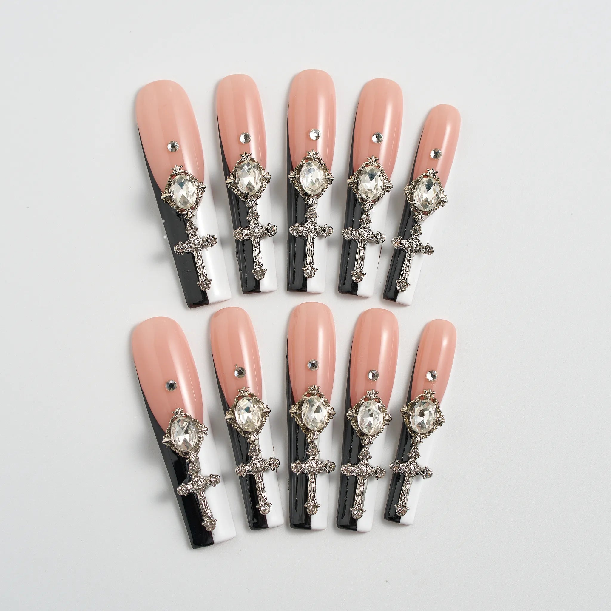 Set of decorative false nails with crosses and crystals on a light gray background