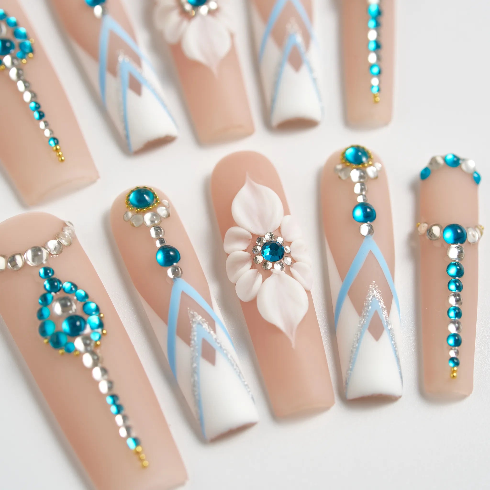 Decorative false nails with blue, white, and gold designs on a light background