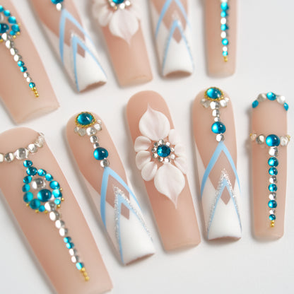 Centered view of ‘Frost Waltz’ long square press-on nails featuring 3D white floral design, blue rhinestones, silver beads, and geometric white-blue detailing.
