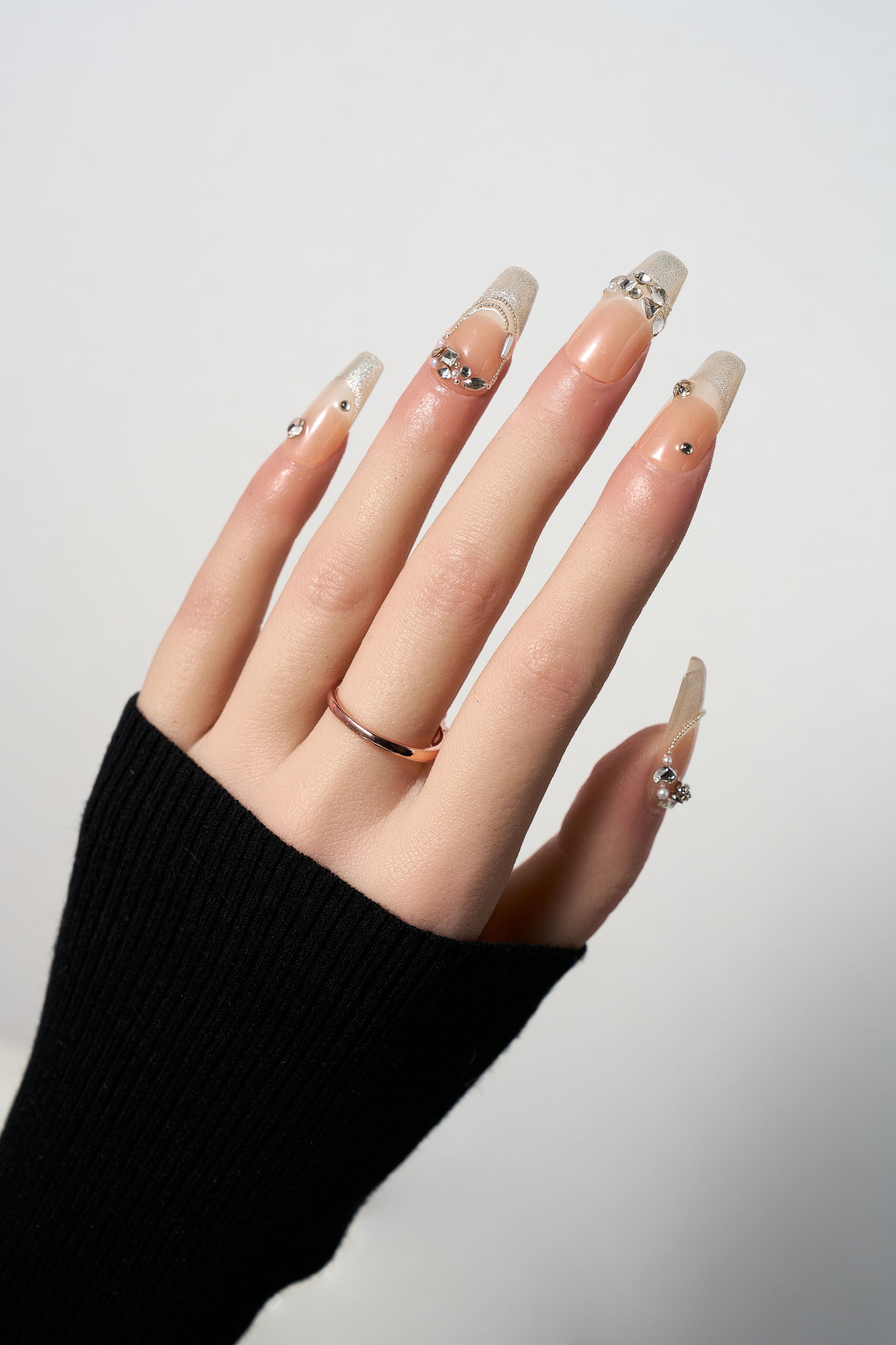 Gilded Heiress luxury press-on nails featuring a nude base with shimmering gold glitter tips and sparkling rhinestone accents in a long coffin shape.