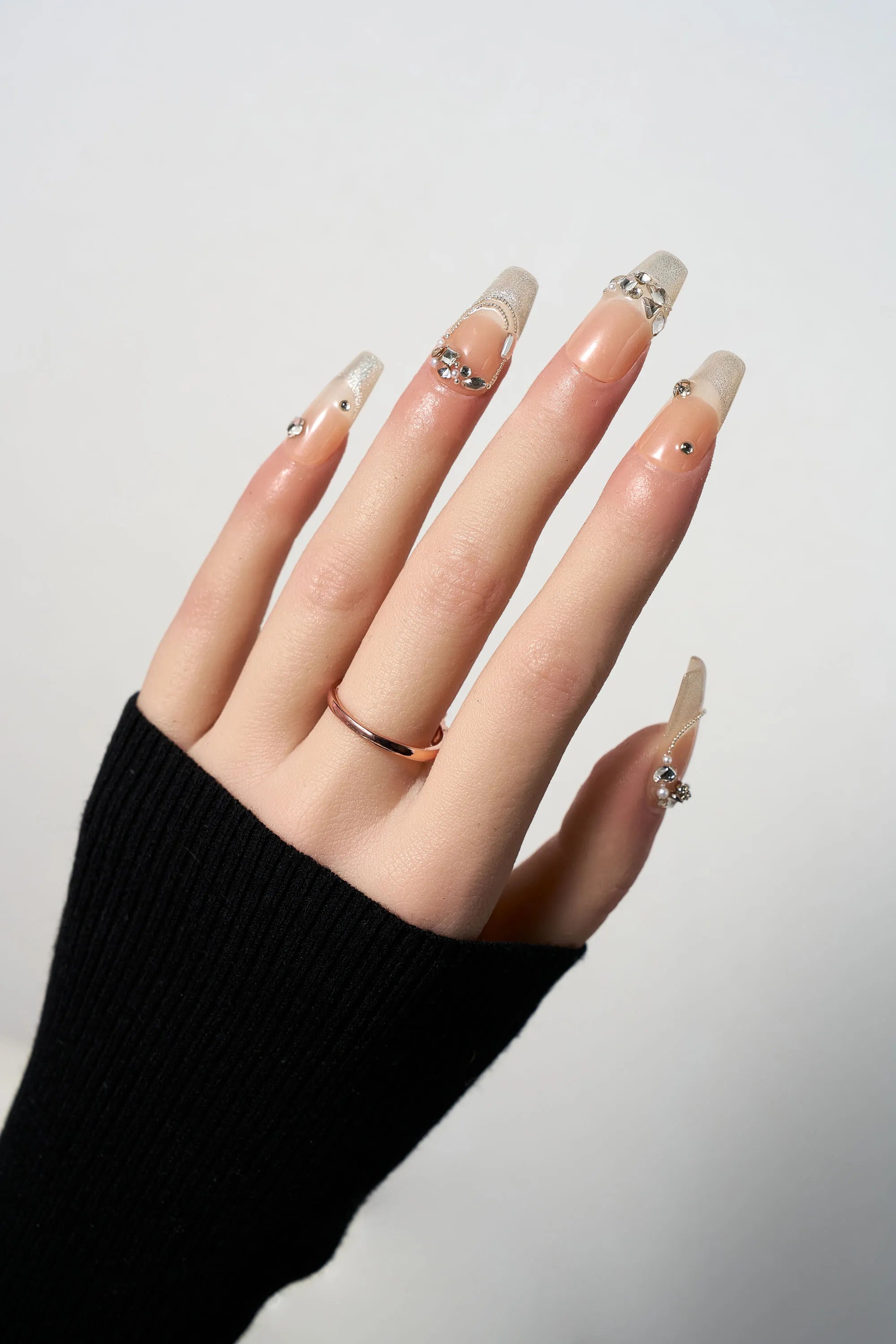 Gilded Heiress luxury press-on nails featuring a nude base with shimmering gold glitter tips and sparkling rhinestone accents in a long coffin shape.