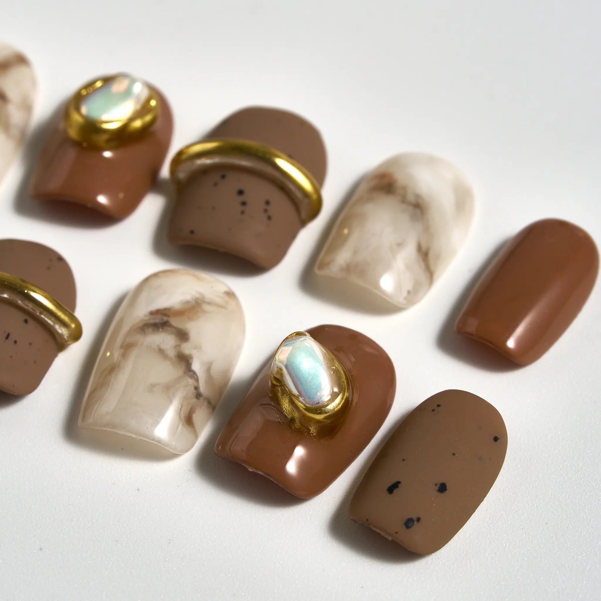 Set of brown and beige nail art designs with gold accents on a white background