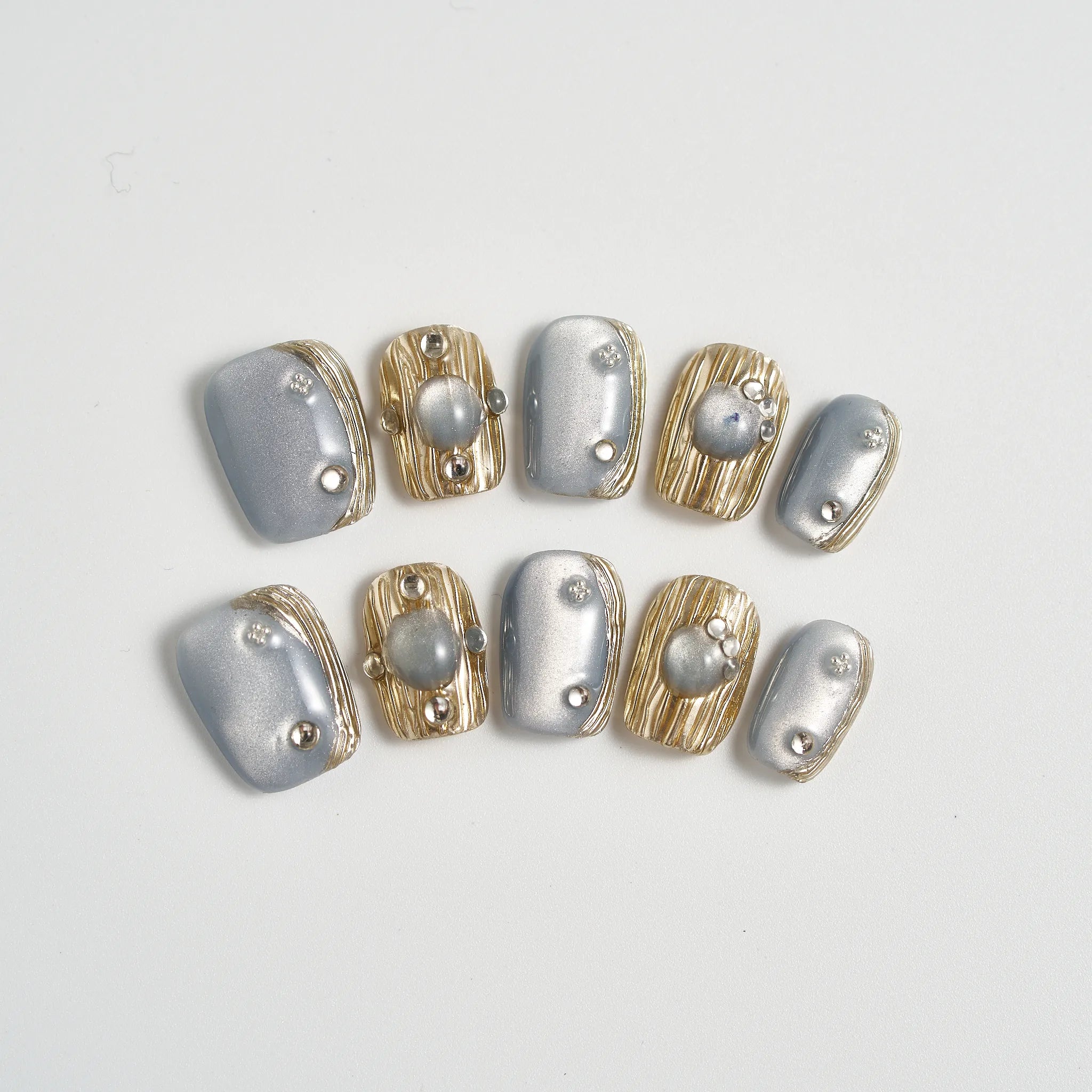 Set of silver and gold nail art decorations on a light gray background