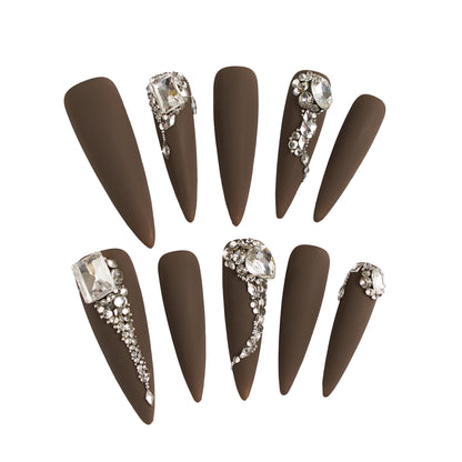 Set of long stiletto matte brown nails with rhinestone and crystal embellishments, displayed on a white background.