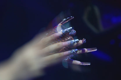 Divine Plea press-on nails with large silver crystal crosses and nude base, captured in a ghosted double-exposure effect against a dark background.
