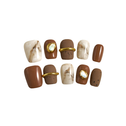 Set of MiuNail Golden Dune press-on nails with marble brown, cream, and gold metallic accents, displayed on a white background.