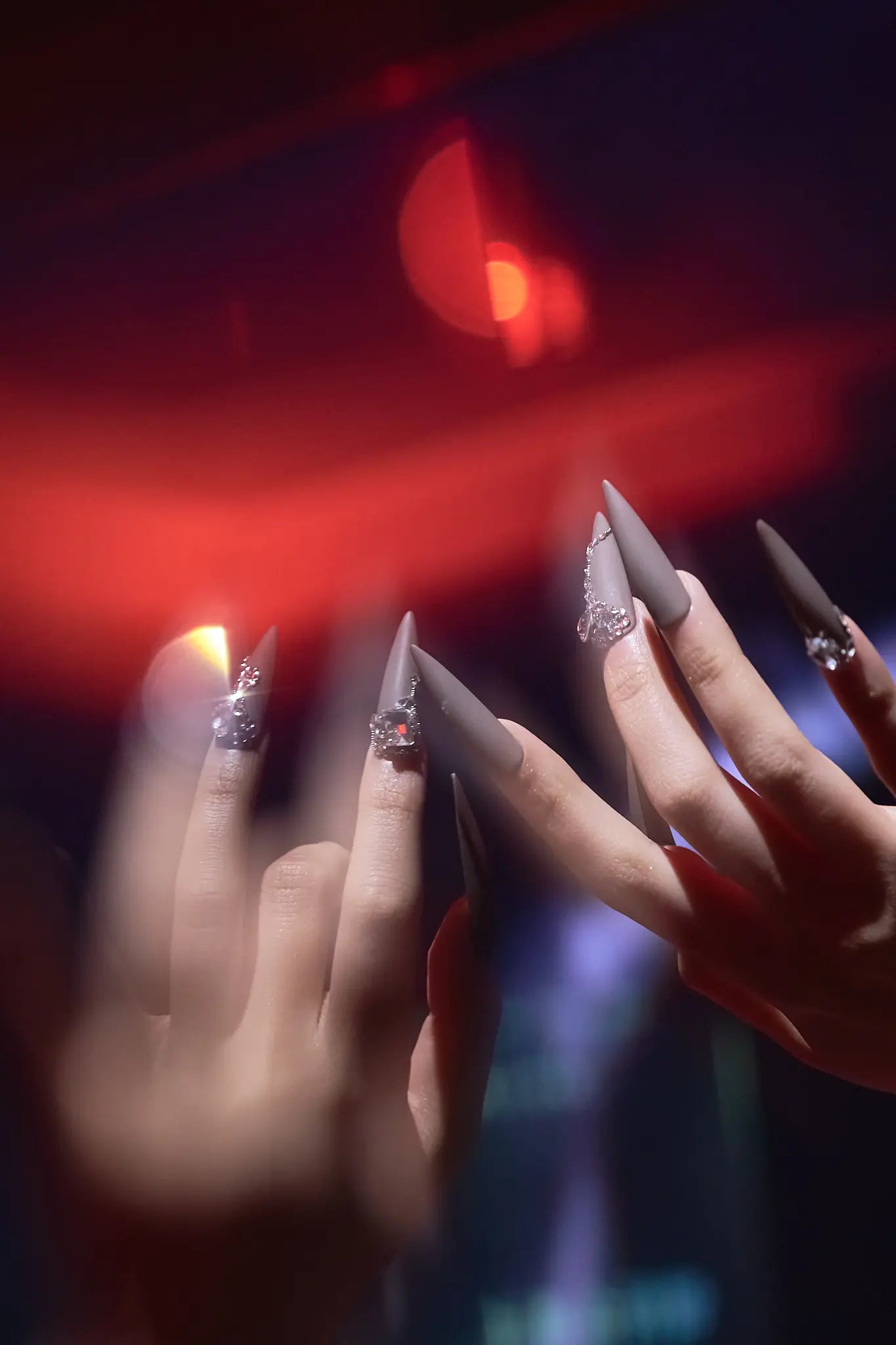 long matte stiletto press on nails with gemstone accents under red light