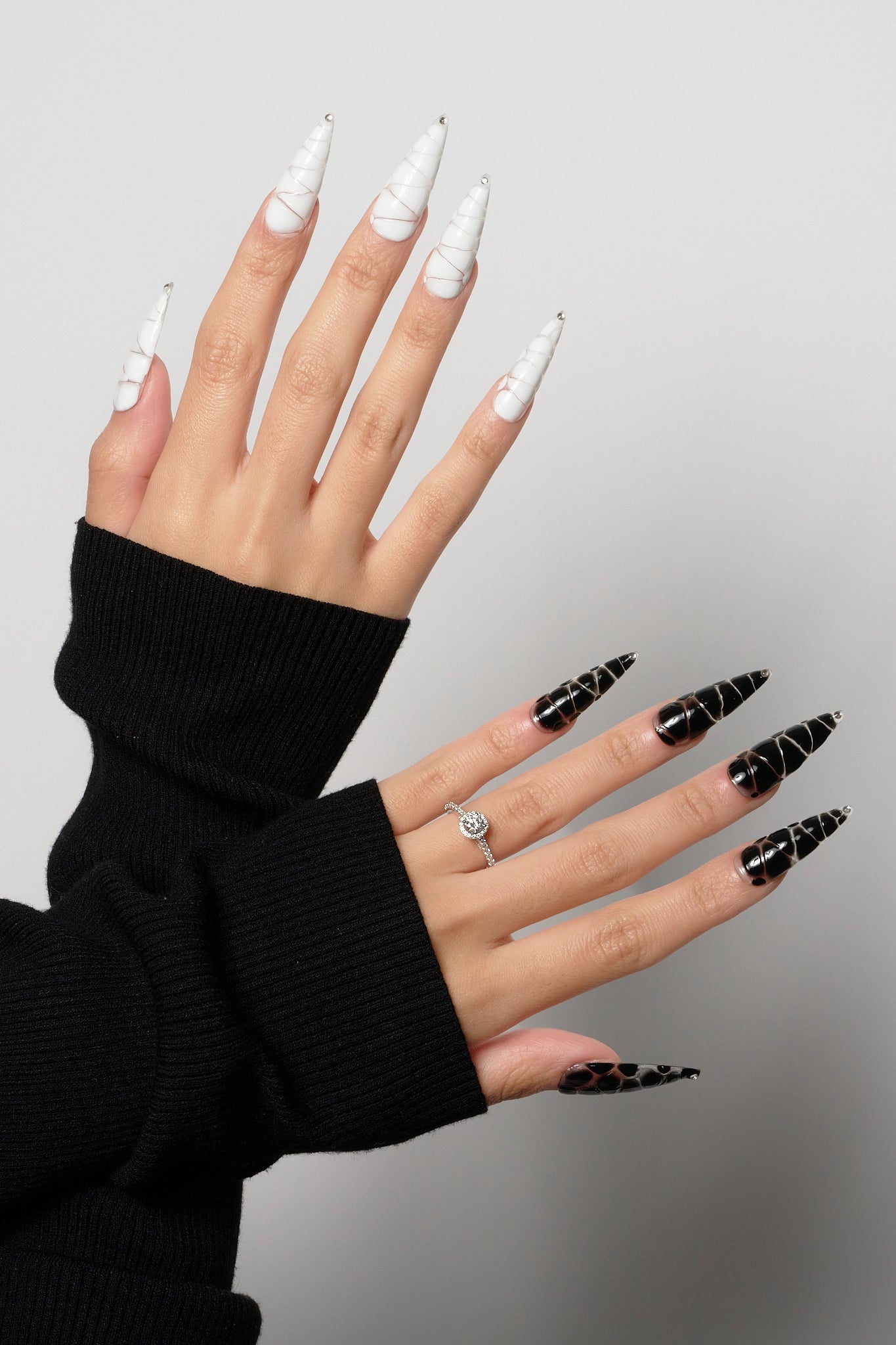 MiuNail Venom Twist press-on nail set featuring sculptural black and white spiral shells with metallic chrome tips, displayed on a white background.