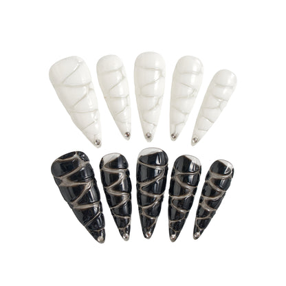 MiuNail Venom Twist press-on nail set featuring sculptural black and white spiral shells with metallic chrome tips, displayed on a white background.