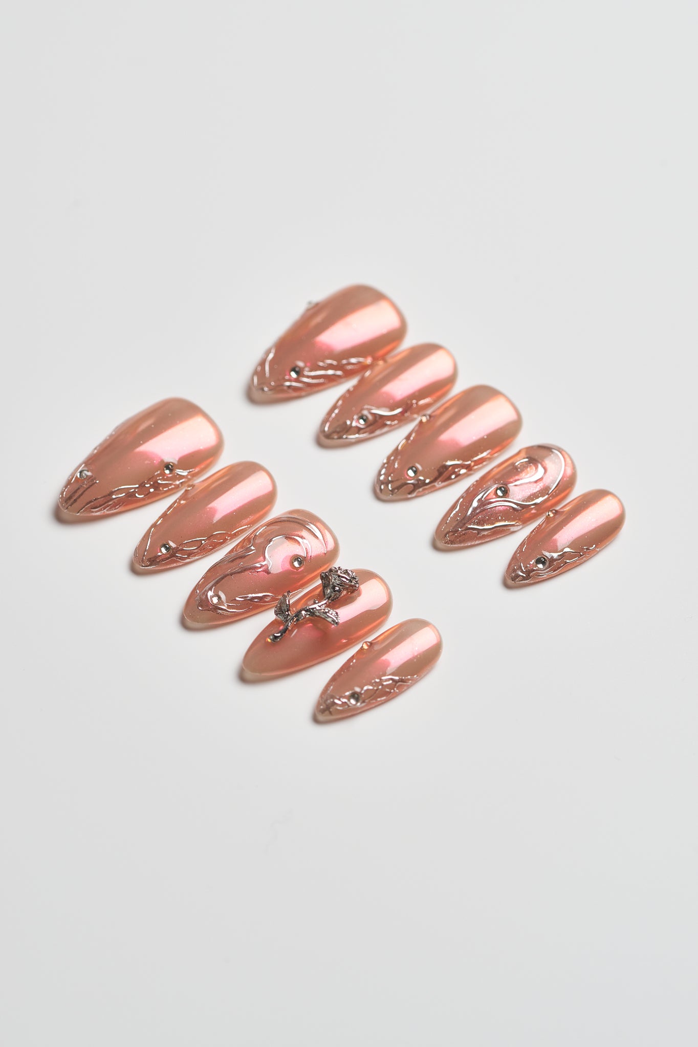 Set of rose gold nail art decorations on a light gray background