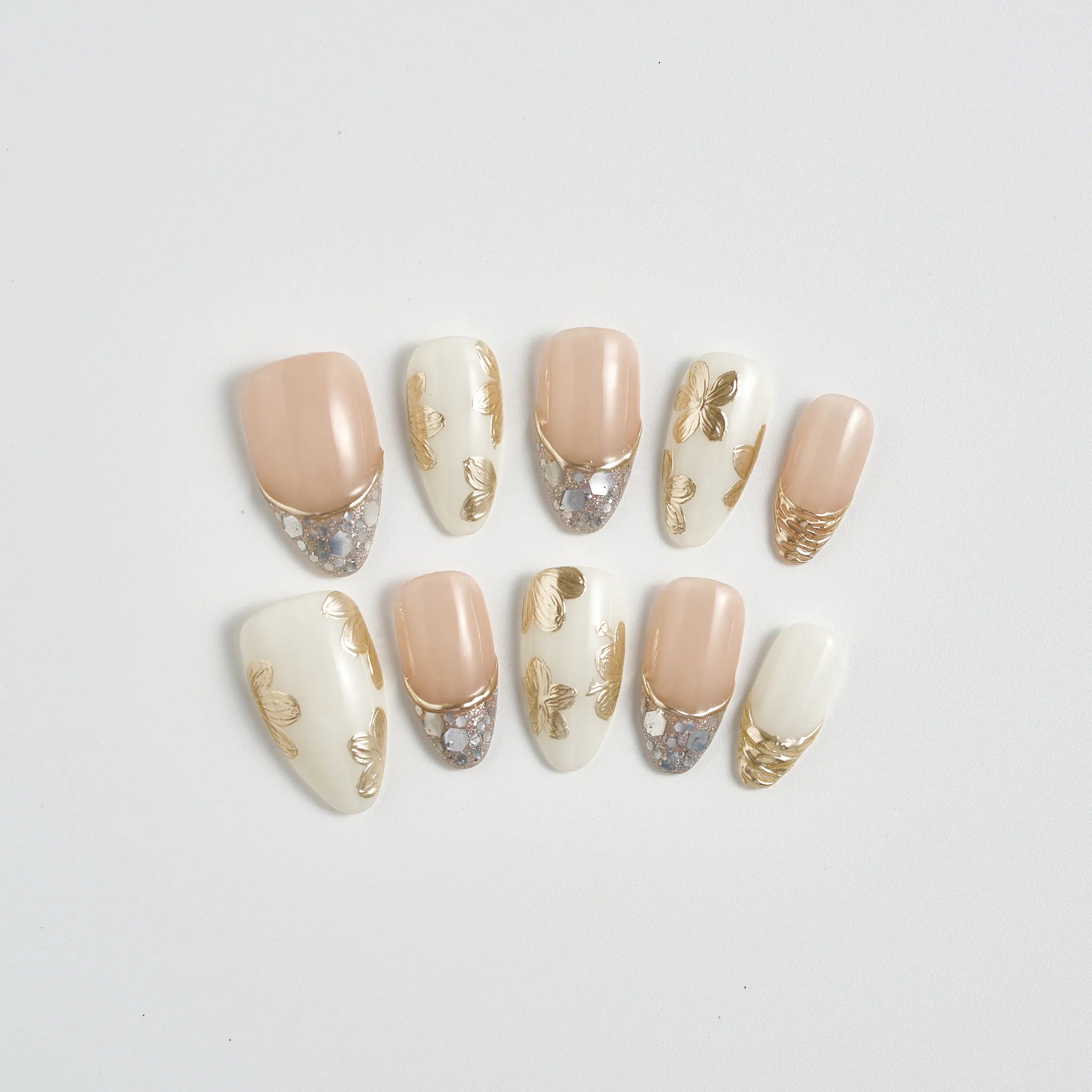 Set of decorative false nails with gold accents on a light gray background
