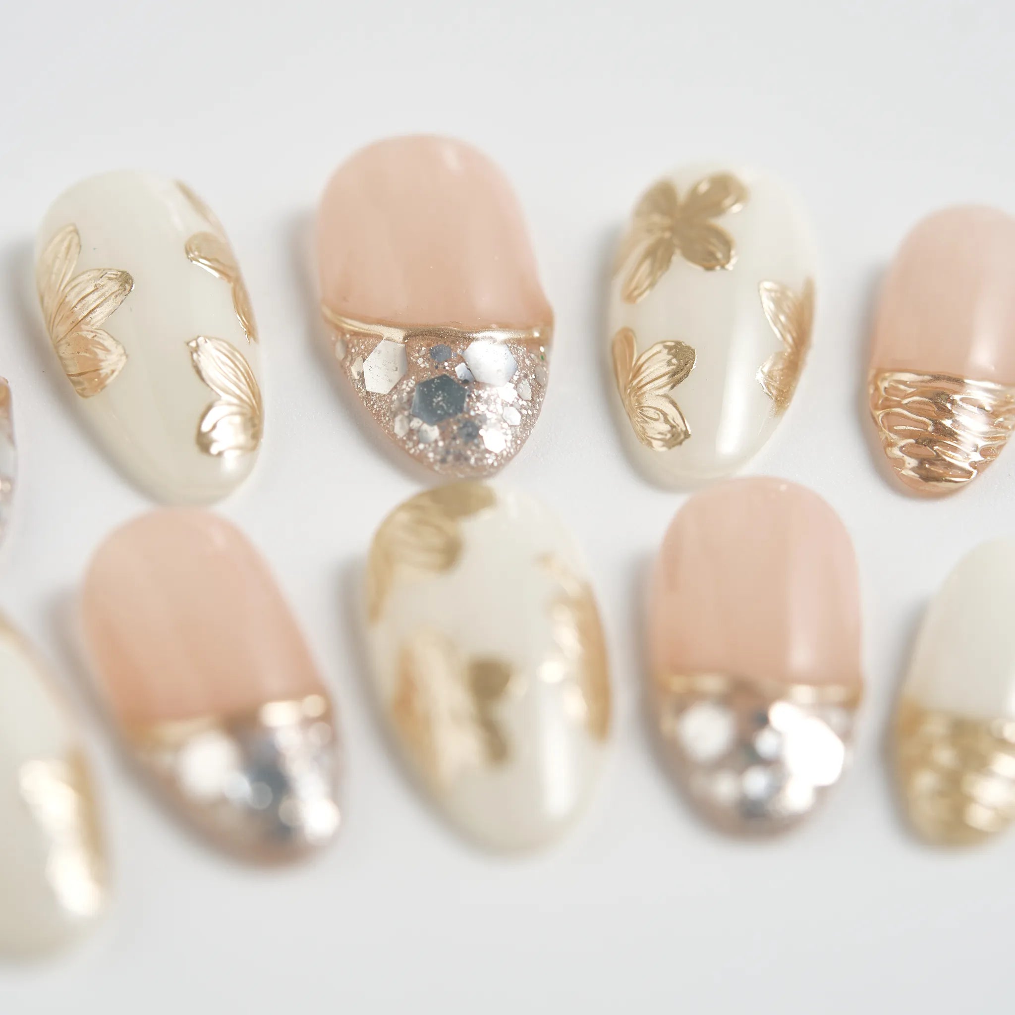 Nail art with gold, silver, and beige polish on a white background