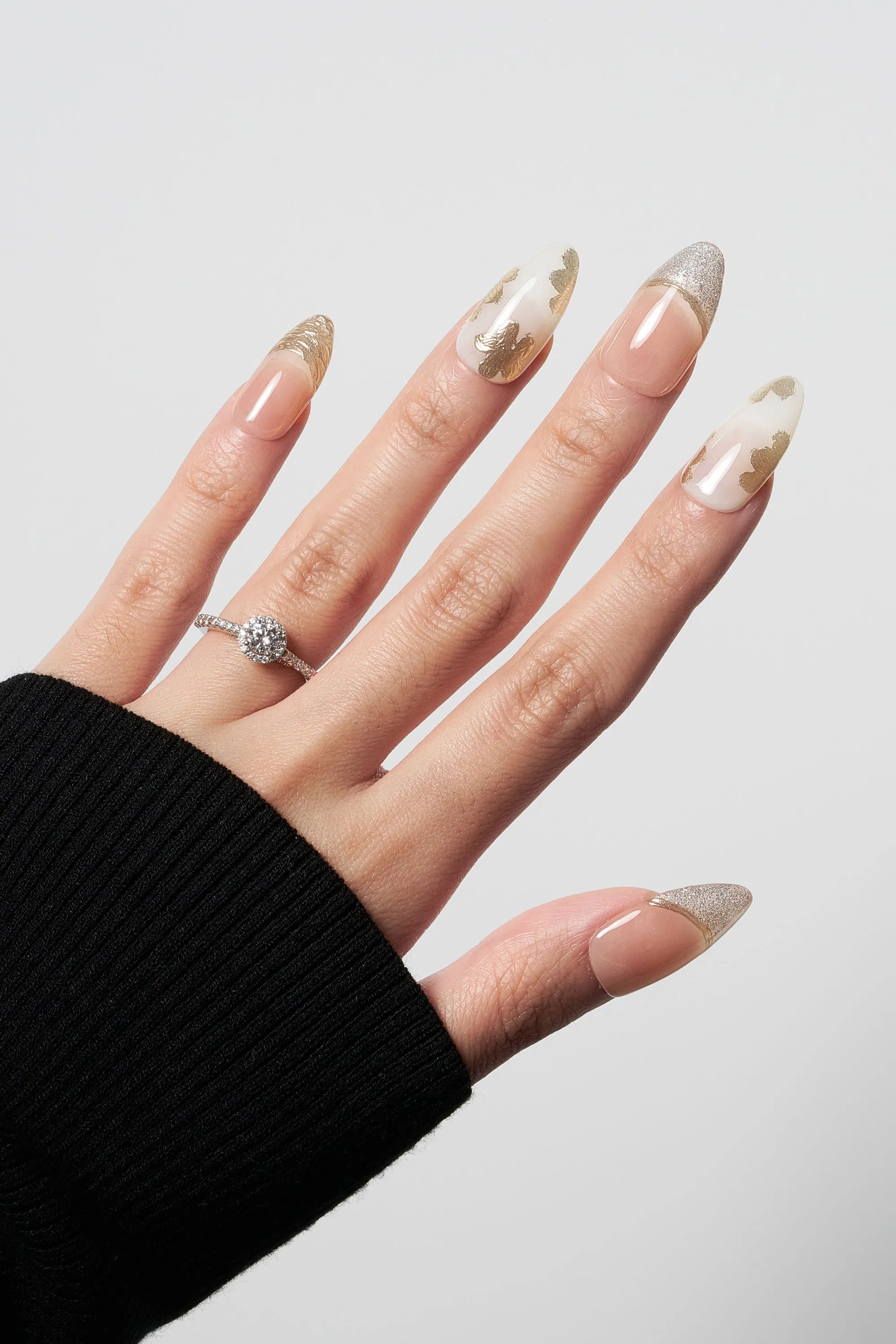 Petal Bloom almond-shaped press-on nails featuring elegant gold leaf floral art on a milky white base, paired with shimmering gold glitter French tips.