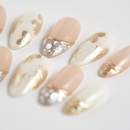 Close-up of Petal Bloom press-on nails with gold and silver accents on a light background