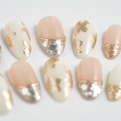 Close-up of Petal Bloom press-on nails with gold and silver accents on a white background.