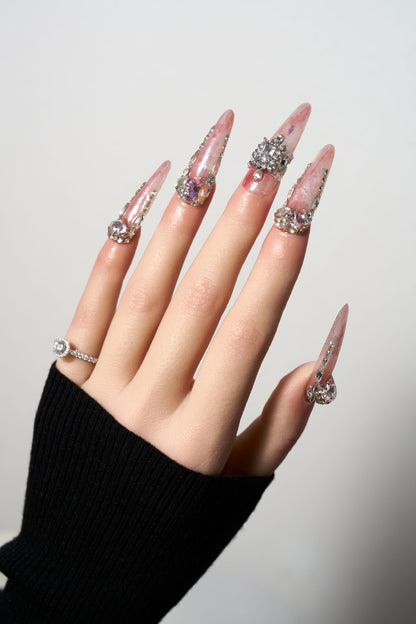 Princess Relic reusable extra-long stiletto press-on nails featuring a dreamy iridescent pink marble base, heavily adorned with luxury silver crystal clusters, a large 3D star-shaped gemstone, and intricate rhinestone crown accents.