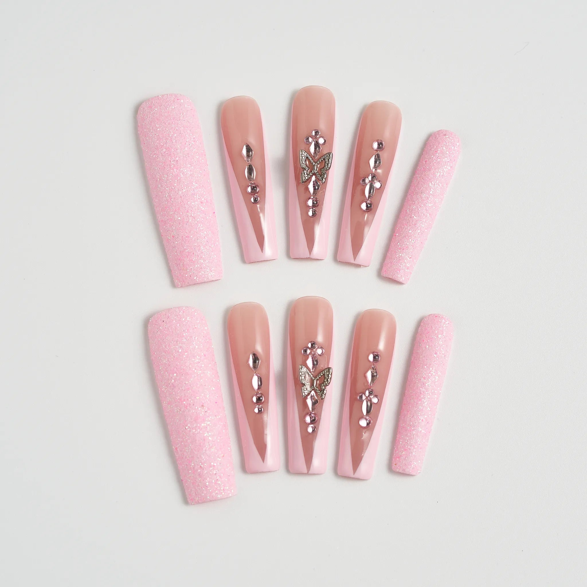 Set of pink nail extensions with decorative elements on a light gray background