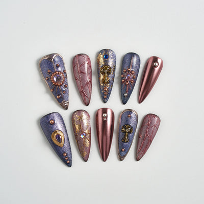 Decorative nail art tips with metallic and gemstone designs on a light gray background