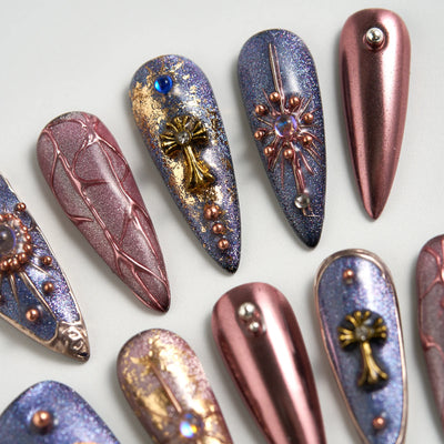 Decorative nail art tips with metallic and gemstone details on a light background